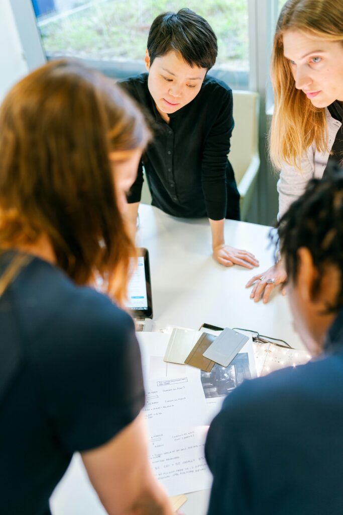 A group of adults engaged in teamwork and planning at an indoor office meeting.