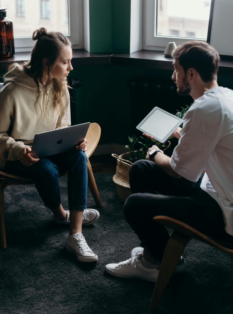 Two adults having a tech-focused discussion in a cozy home setting.