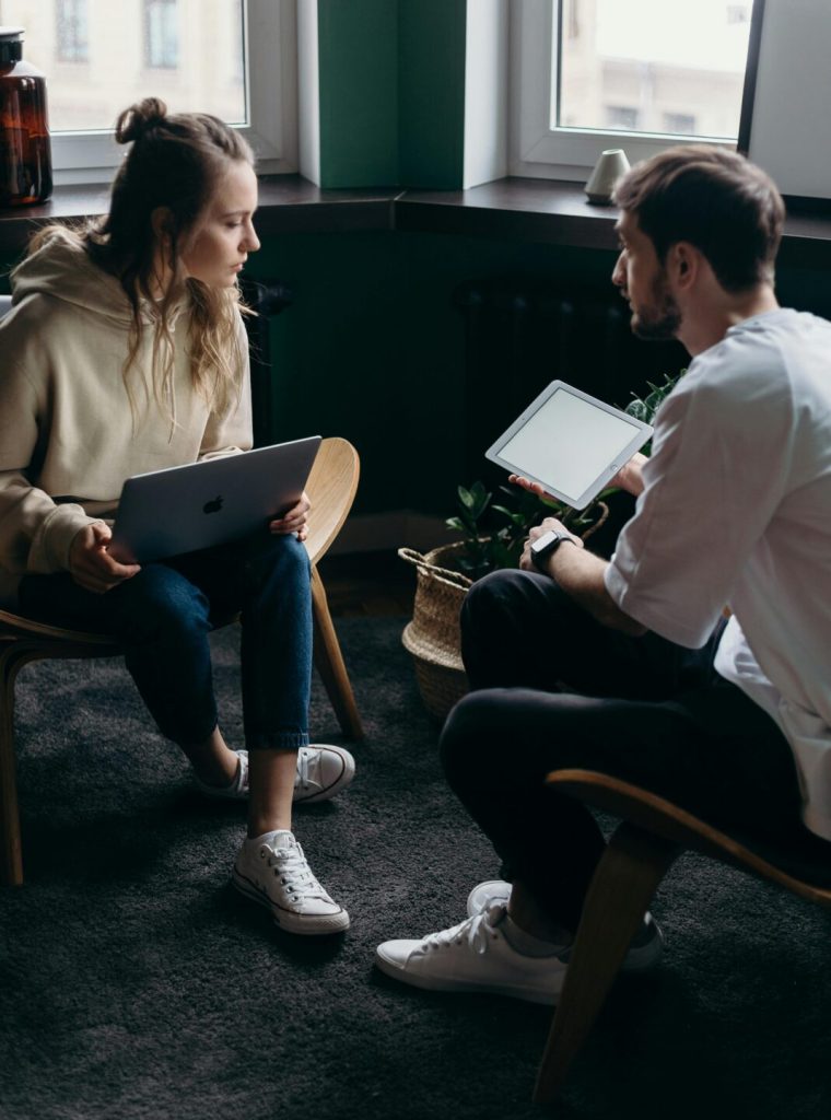 Two adults having a tech-focused discussion in a cozy home setting.