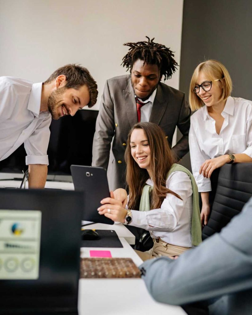 A diverse office team collaborates with technology in a modern workplace.